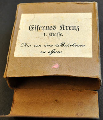 Vaskereszt Első Osztálya kitüntetés doboza. Felirata: „Csak a kitüntetett nyithatja ki”. Forrás: Europeana 1914–1918.