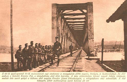 Az eredeti képaláírás: „A 68-ik gyalogezred 11-ik századának egy szakasza a mozgósítás előtti napon, őrségen a Száva-hídnál. Az első sorban a hetedik Kovács Pál, a világháború első hősi halottja. A kép jobboldalán látszó vasuti őrház telefonja mellett érte szerb golyó a háború első napján Knerler János főhadnagyot, a világháború első sebesültjét. A híd közepén, fehér zubbonyban szerb katona áll őrt.”